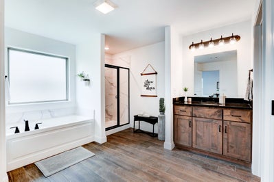Large primary bathroom with tub, shower and sink with stained cabinets