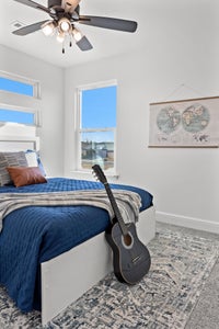 Bedroom with blue comforter and dark guitar leaning against the bed