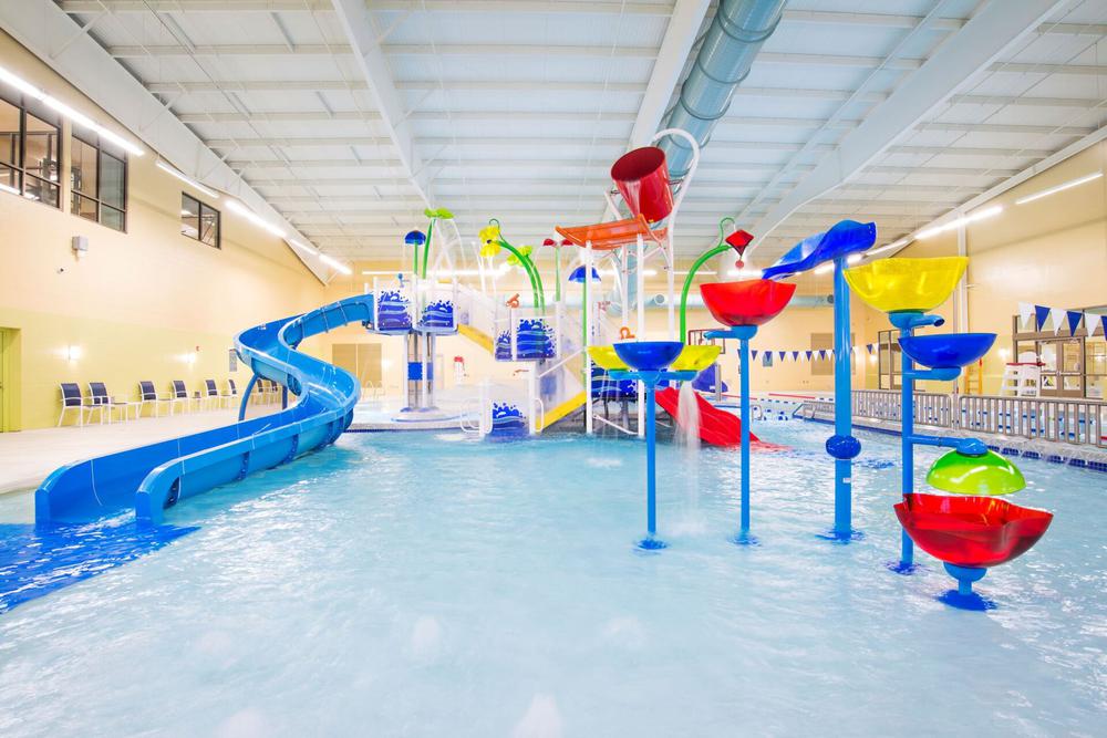 an indoor pool with water slide and colorful water toy structures