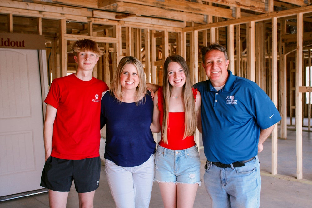 Family shown smiling in their new home under construction