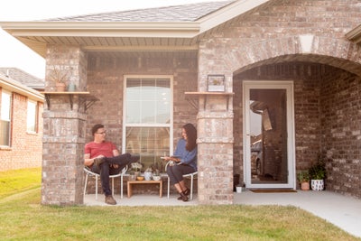 Man and woman seen reading a book on the front porch of their new home