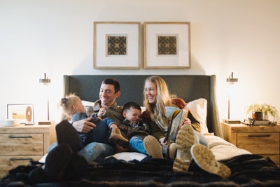 Family of four sitting on bed laughing